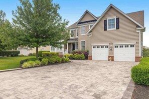A two-story house with a garage, a driveway, and a well-maintained lawn. - Bethany Lakes home with waterfront views, pool access, tennis, & private patio (Bethany Beach)