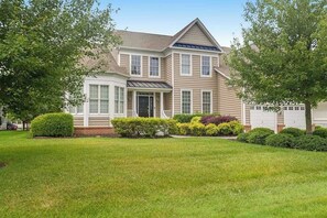 A two-story house with a front porch, a garage, and a well-maintained lawn. - Bethany Lakes home with waterfront views, pool access, tennis, & private patio (Bethany Beach)