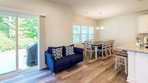 Eine moderne Küche mit Essbereich, ein blaues Sofa mit gemusterten Kissen und großen Fenstern.