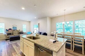 A modern kitchen with granite countertops, a built-in dishwasher, and a dining area with a table and chairs. - Seashore Villas townhouse w/patio, grill & shared community pool (Selbyville)