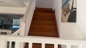 A staircase with wooden steps and white railings, leading to a landing with a wall-mounted decorative item and a framed picture.