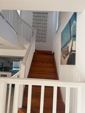 Una escalera de madera con barandillas blancas que conduce a una plataforma con un adorno de pared y un cuadro enmarcado.