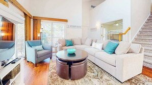 Een moderne woonkamer met een zithoek, een salontafel en een trap.