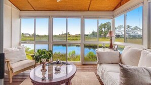 Une véranda dotée de grandes fenêtres, d’un ventilateur de plafond et offrant une vue sur un lac.