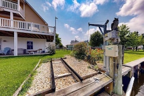 Een huis met een balkon, een tuin met een grindpad, en een steiger die in het water uitsteekt.