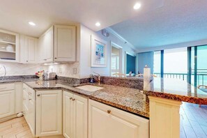 A kitchen with white cabinetry, granite countertops, and a large window. - Sea Colony beachfront 6th-floor condo with 12 pools, 2 hot tubs, private beach (Bethany Beach)