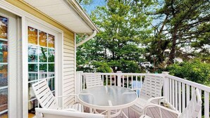 Eine überdachte Terrasse mit einem runden Tisch und weißen Stühlen, umgeben von einer weißen Brüstung.