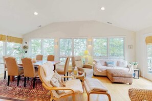 A spacious living area with a dining table, multiple chairs, a sofa, and a coffee table. - Town of South Bethany Beach home with sunroom and water views - dogs ok (Bethany Beach)