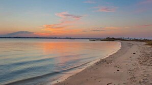 Ein Strand mit ruhigem Wasser und blauem Himmel.