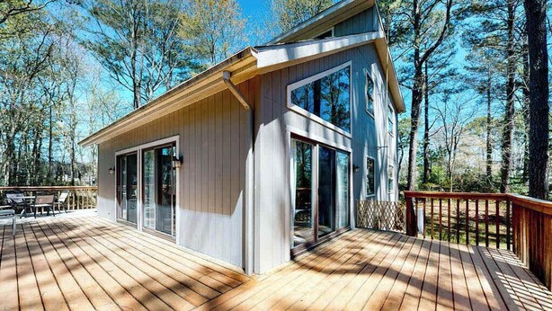 A wooden deck with a glass-enclosed room, surrounded by trees. - Secluded, 4-BR, dog-friendly home, private beach (Bethany Beach)