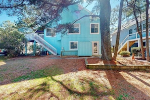 A two-story house with a blue exterior, a wooden staircase, and a well-maintained yard with trees and a small garden. - Town of South Bethany home with bikes, W/D, & AC - dogs ok (Bethany Beach)