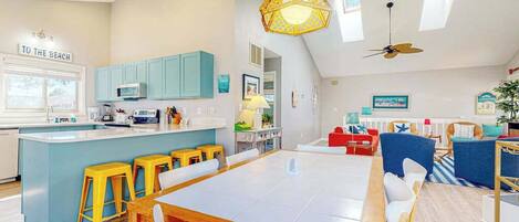 A modern kitchen with a central island, bar stools, and a dining area with a large table.
