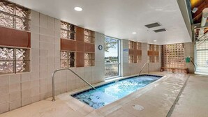 Ein Hallenbad mit Fliesenwänden, einer Uhr und einer Sitzbank.