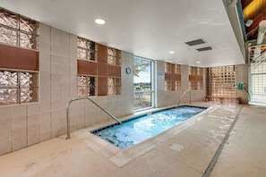 Ein Hallenbad mit Fliesenwänden, einer Uhr und einer Sitzbank.