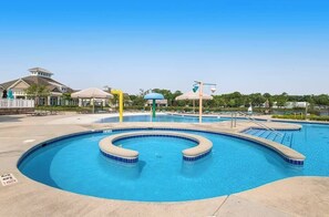Ein Schwimmbecken mit kreisförmigem Design, einer überdachten Lounge und einem Pavillon.