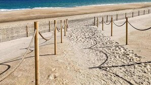 Una playa arenosa con una cerca de madera y una barrera de cuerda.
