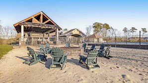 Ein Pavillon am Strand mit Adirondack-Stühlen, einer Feuerstelle und einem überdachten Sitzbereich.