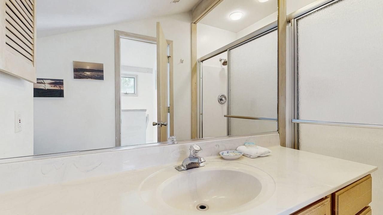 Un baño con un espejo grande, un lavamanos y una ducha.