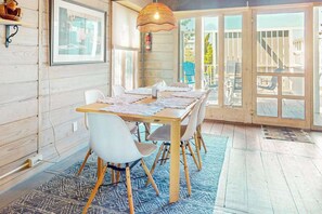 A dining area with a table set for four, surrounded by white chairs, a blue patterned rug, and a hanging light fixture. - Atlantic Watergate townhome steps from the beach, oceanfront balconies (Bethany Beach)