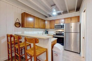 A kitchen with wooden cabinets, a stainless steel refrigerator, a microwave, and a sink.
