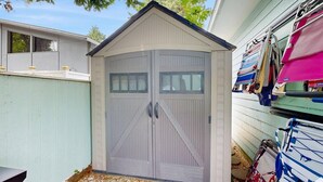A garage with two doors, a window, and a ladder leaning against the wall. - Experience Classic Dewey Charm at This Coastal Retreat with Hot Tub (Dewey Beach)