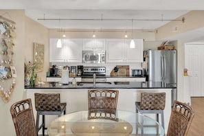 Una cocina moderna con armarios blancos, electrodomésticos de acero inoxidable y una mesa de comedor de vidrio.