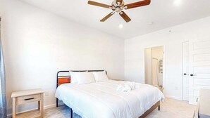 Ein Schlafzimmer mit Bett, Nachttisch, Deckenventilator und Tür.