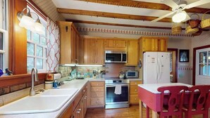 Una cocina con armarios de madera, un refrigerador de acero inoxidable, un microondas y un fregadero.