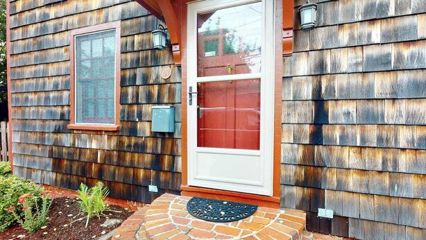 Una casa de madera con puerta roja, una ventana y un buzón.