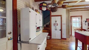 Una cocina con piso de madera, un refrigerador blanco y una escalera.