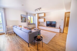 Un salon moderne avec un canapé, un téléviseur et une petite table sur laquelle se trouve un panier.
