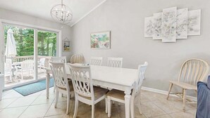 Een eetruimte met een witte tafel en stoelen, een kroonluchter en kunst aan de muur.