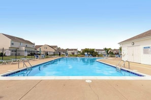 A rectangular swimming pool with a tiled edge, surrounded by lounge chairs and a fence. - Wedgefield house w/ free WiFi, gas grill, outside shower & community pool (Ocean View)