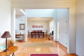 A spacious room with a wooden floor, a dining table with chairs, a lamp, and a framed picture on the wall. - Wedgefield house w/ free WiFi, gas grill, outside shower & community pool (Ocean View)