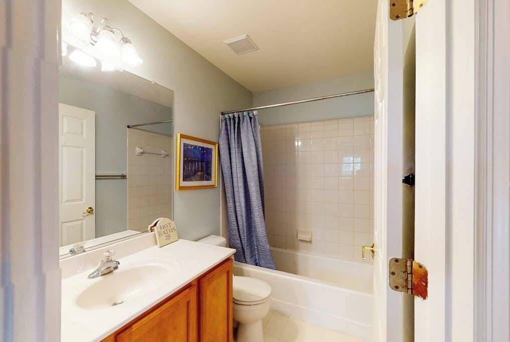 A bathroom with a sink, mirror, toilet, and bathtub.