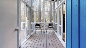 A covered deck with a table and chairs, large windows, and a view of trees. - Middlesex Beach house w/ outside shower, grill & community private beach (Bethany Beach)