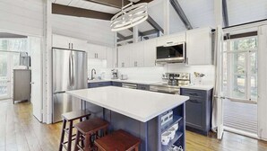 A modern kitchen with a large island, stainless steel appliances, and a pendant light. - Middlesex Beach house w/ outside shower, grill & community private beach (Bethany Beach)