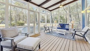 A covered outdoor area with wooden flooring, a sofa, chairs, and a table. - Middlesex Beach house w/ outside shower, grill & community private beach (Bethany Beach)