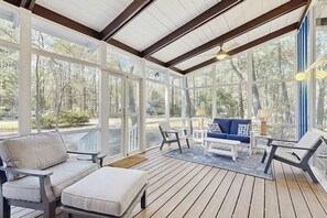 A covered outdoor area with wooden flooring, a sofa, chairs, and a table. - Middlesex Beach house w/ outside shower, grill & community private beach (Bethany Beach)
