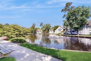 Ein Wohngebiet mit Teich, Häusern und einer Bank.