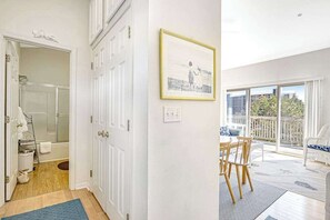 A room with a shower, a dining area with a table and chairs, and a balcony with a view.