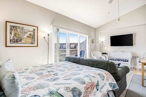 A bedroom with a bed, a television, a chair, and a window.