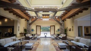 A spacious lobby with a central seating area, a high ceiling with exposed beams, and a view through a large archway. - Garza Blanca Preserve Resort & Spa (Puerto Vallarta)