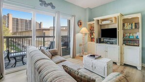 Una sala de estar con un sofá, una mesa de centro, un televisor y una estantería.