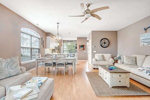 Ein geräumiges Wohnzimmer mit Essbereich, Deckenventilator und großem Fenster.
