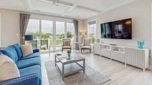 Een ruime woonkamer met een grote televisie, comfortabele zithoek en een balkon met uitzicht.