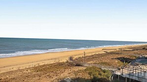 Una platja amb un passeig marítim, sorra i l'oceà.