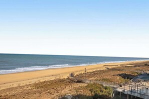 Ein Strand mit Promenadenweg, Sandstrand und dem Meer.