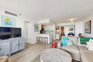 Ein modernes Wohnzimmer mit Fernseher, Sofa und rundem Couchtisch.