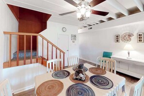 A dining area with a table, chairs, a decorative centerpiece, and a staircase leading to an upper level.